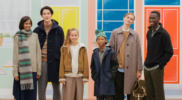 Adults and children pose in front of pastel background. They are wearing fall and winter outfits.